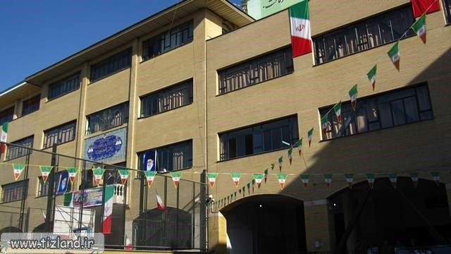 نمای بیرونی ساختمان دبیرستان باقرالعلوم با پرچمهای ایران
