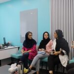 گروهی از دانش‌آموزان و مربی در حال برگزاری یک جلسه‌ی آموزشی و بحث گروهی در اتاقی با دیوارهای آبی روشن