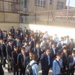 دانش‌آموزان و کادر آموزشی در حیاط مدرسه برای مراسم اجتماع رسمی جمع شده‌اند