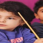 دو کودک در حال شرکت در فعالیتی گروهی یا مراسم مدرسه‌ای با پس‌زمینه صورتی