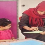 معلمی در حال تدریس یک دانش‌آموز کوچک در طول یک جلسه آموزشی یک‌به‌یک با تمرکز بر یک فعالیت یادگیری