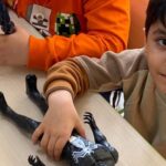 بچه‌های کوچکی در حال بازی تعاونی و ساختمان‌دهی با اسباب‌بازی‌های رنگی، در محیط داخلی کلاس درس