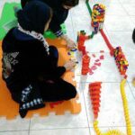 دانش‌آموز در حال ساخت سازه رنگین با بلاک‌های لگو در برنامه‌ی تعاونی کلاسی