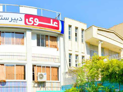 نمای بیرونی ساختمان مدرسه علوی با تابلوی قرمز رنگ و واجهه‌ی معماری مدرن