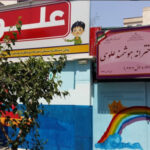 نمای ورودی اصلی مدرسه با سردر قرمز و دیوار نقاشی‌شده رنگی