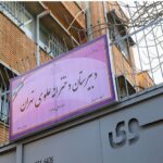 تابلوی نام دبستان دخترانه علوی منیریه با رنگ بنفش و متن فارسی بر روی ورودی ساختمان