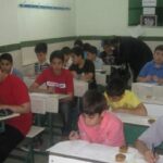 دانش‌آموزانی در حال انجام یک فعالیت گروهی در کلاس درس با کار روی جعبه‌های کوچک روی میز