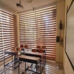 نمای عمومی کلاس درس با میزها و صندلیهای دانشآموزان، دیوارهای با محتوای آموزشی و پنجرههای بزرگ