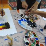 دانش‌آموزان در حال انجام فعالیت هنری و نقاشی با استفاده از رنگ‌های مختلف و پالت‌های رنگ در کلاس درس