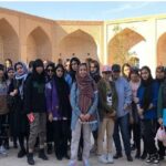 گروهی از دانش‌آموزان در حیاط یک ساختمان معماری سنتی برای عکس تیمی
