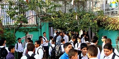 دانش‌آموزان متعددی در حیاط یا فضای باز مدرسه برای یک مراسم یا رویداد جمع شده‌اند
