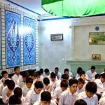 دانش‌آموزانی در کلاس درس در حال شرکت در یک فعالیت یادگیری گروهی همراه معلم