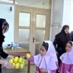 مراسمی درون‌مدرسه‌ای با دانش‌آموزان دختر لباس رسمی‌پوش و یک معلم یا ناظم، به نظر حین یک رویداد یا مراسم رسمی