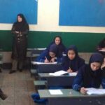 دانش‌آموزان دختر در حال نوشتن و مطالعه در کلاس درس با معلم