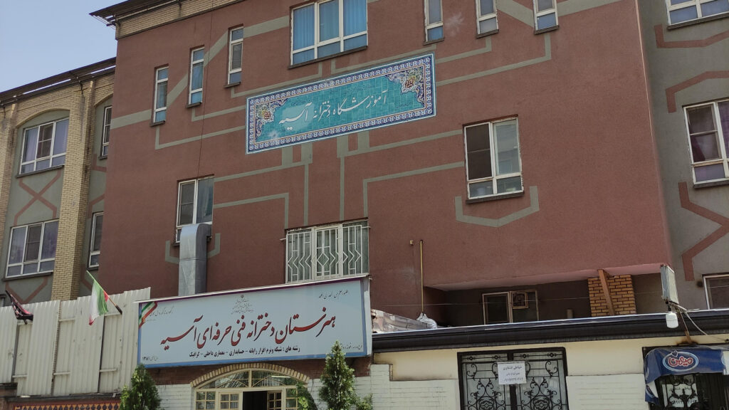 نمای بیرونی ساختمان هنرستان دخترانه آسیه با تابلوی سردر مدرسه