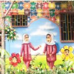 نمای بیرونی ساختمان مدرسه با نقاشی دیوار رنگین و درام تر شده‌ی دو دختر دانش‌آموز با حجاب در میان گیاهان و گل‌های بهاری