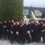گروهی از دانش‌آموزان دختر در پوشش یکسان سیاه برای عکس یادی در حیاط مدرسه موضع گرفته‌اند.