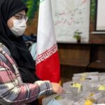 دختری با روسری و ماسک در حال شرکت در صندوق‌رای در فعالیت انتخابات مدرسه، پرچم ایران در پس‌زمینه