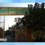 درب ورودی مدرسه با تابلوی دائمی فارسی و دیوار سبز پوشش یافته با گیاهان