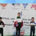 سه دانش‌آموز برنده مدال روی سکو مدال‌خوری در مسابقه رباتیک آسیای مرکزی ۲۰۱۹، با بنر رسمی رویداد و لوگوهای سازمان‌های سرپرست در پس‌زمینه