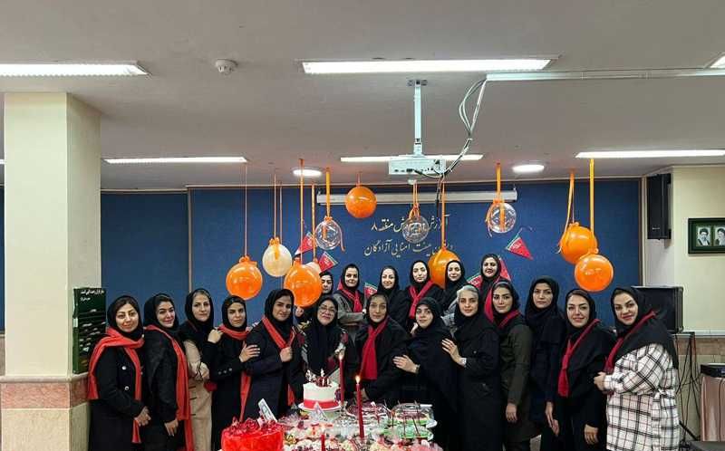 گروهی از دانش‌آموزان دختر در حال جشن‌گیری در کلاس با کیک و تزئینات نارنجی رنگ