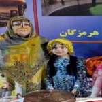 دانش‌آموزان در لباس‌های سنتی و رنگی در حال شرکت در مراسم فرهنگی مدرسه با بنر و تزئینات رویداد