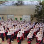 تجمع دانش‌آموزان دختری با لباس یکسان در حیاط مدرسه برای شرکت در یک مراسم یا آیین مدرسه‌ای