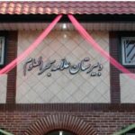 نمای سردر ورودی مدرسه با تابلوی نام و تزیینات بنر صورتی و سبز
