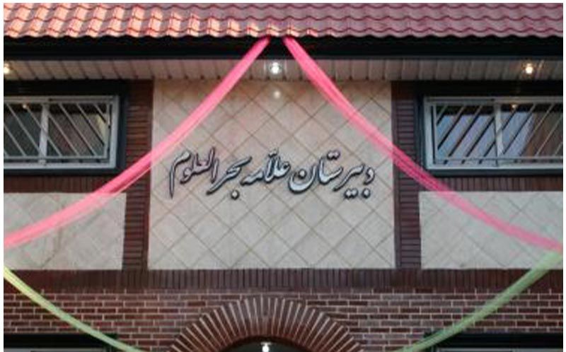 نمای سردر ورودی مدرسه با تابلوی نام و تزیینات بنر صورتی و سبز