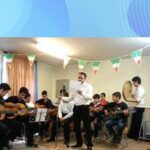 گروهی از شاگردان در حال اجرای موسیقی با گیتار و سازهای دیگر در یک حفل مدرسه‌ای با تزیینات رنگی و نظارت معلم