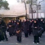 گروهی از دانش‌آموزان با یکنواخت مدرسه در حیاط ایستاده در حال شرکت در یک رویداد یا مراسم مدرسه‌ای