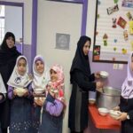 دانش‌آموزان در حین دریافت غذا در بوفه مدرسه، نشسته بر روی میز غذاخوری با سرویس‌دهنده