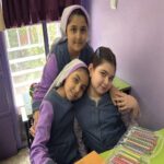 دانش‌آموزان دختر در کلاس درس مجهز به میز، کتاب‌های درسی و پنجره‌های روشن