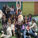 دانش‌آموزان در حین شرکت در جشن مدرسه‌ای با شخصیت استقبال‌کننده و بادکنک‌های رنگین‌رنگ