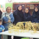 گروهی از دانش‌آموزان و معلمان در حال شرکت در فعالیت ساخت‌وساز هندسی STEM با ساختارهای معماری هندسی بر روی میز در کلاس
