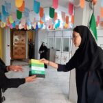 دو دانش‌آموز در حال نمایش پروژه‌ی خود در راهرو مدرسه با تزئینات رنگی و پرچم ایران