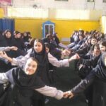 دانش‌آموزان در حیاط مدرسه در حال انجام تمرین دسته‌جمعی با دستان دراز شده