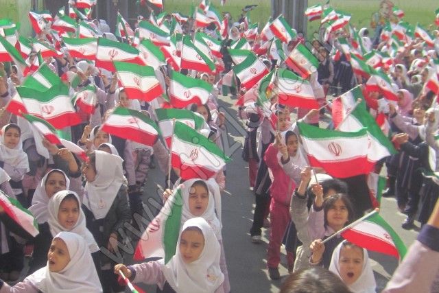 دانش‌آموزان دختر دبستان در مراسم ملی با پرچم‌های ایران