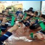 دانش‌آموزان در حال عکس‌برداری گروهی در داخل کلاس درس مجهز به تخته‌سفید و جداول آموزشی دیواری