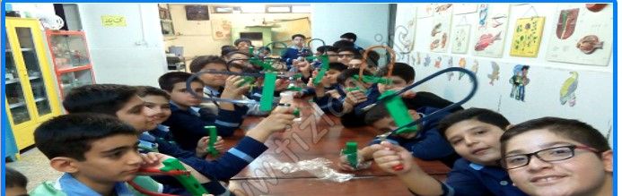 دانش‌آموزان در حال عکس‌برداری گروهی در داخل کلاس درس مجهز به تخته‌سفید و جداول آموزشی دیواری
