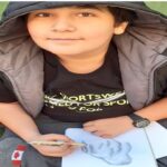 دانش‌آموزی با دستکش و فرم‌های ثبت علمی در حال انجام یک آزمایش یا مشاهده میدانی در حیاط مدرسه