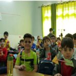 دانش‌آموزان در حال انجام یک بازی یا فعالیت تعاملی با نوارهای رنگی در کلاس درس
