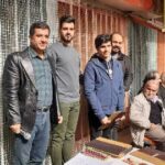 گروهی از معلمان و دانش‌آموزان در حال حضور در یک نشست آموزشی گروهی کنار میز در مدرسه