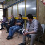 گروهی از افراد در یک نشست گروهی نشسته‌اند و اسناد و مستندات را بررسی و بحث می‌کنند.