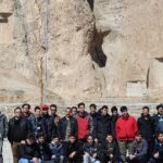 گروهی از دانش‌آموزان در مقابل دیوار سنگی برای عکس یادیاری