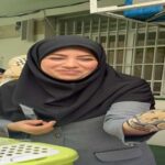دانش‌آموزی در حال نمایش دستانش با طرح‌های هنری رنگی در یک فعالیت مدرسه‌ای