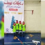 چهار دانش‌آموز دختر در لباس ایمنی سبز در کنار بنر رویداد مسابقه رویین کانون فرهنگی تربیتی پردیس