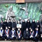 گروهی از دانش‌آموزان در حال عکس‌گرفتن جمعی جلوی مجسمه‌ای داخل ساختمان مدرسه