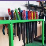 قفسه سبز رنگ حاوی ابزارهای نقاشی شامل خط‌کش‌های رنگی، مسطره‌ها و قلم‌های مختلف برای کلاس‌های هنری