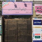 نمای بیرونی درب ورودی مدرسه با تابلوی نام و برنامه‌های آموزشی بر روی دیوار